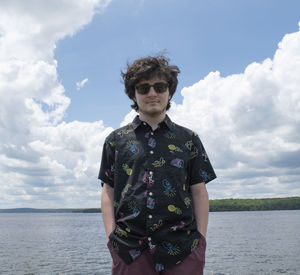 Portrait of man standing by river against sky