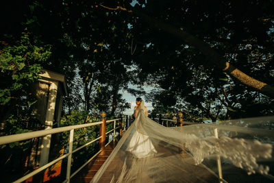 Bride standing by railing on bridge against sky