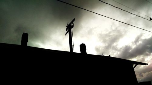 Low angle view of silhouette building against cloudy sky