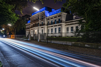 Light trails on street against buildings at night