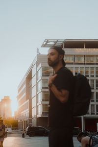 Portrait of young man standing against building