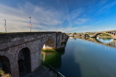 Arch bridge over river against sky