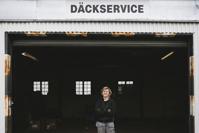 Female mechanic in front of car garage