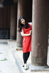 Full length of young woman standing by column