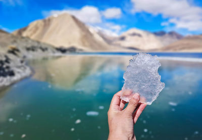 Close-up of person holding ice against lake