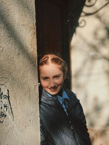 Portrait of smiling girl standing by wall