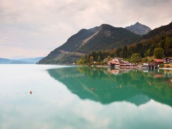 Village on the bank of alps lake. high mountain peaks in mirror of gren water level. 