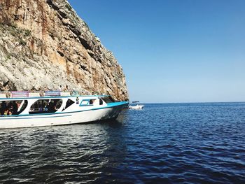 Boat sailing in sea against clear sky