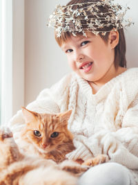 Kid with decorative star tinsel for christmas tree hugs cute ginger cat. new year, christmas.