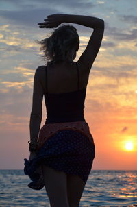 Rear view of woman standing against sky during sunset