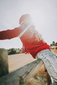 Side view of woman standing on rock against sky