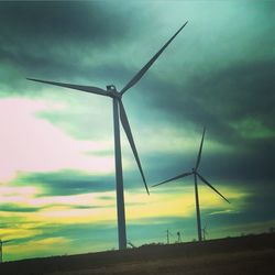 Windmill on field against cloudy sky