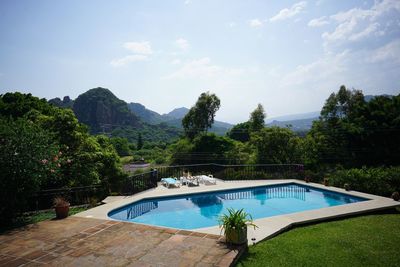 Swimming pool by trees against sky