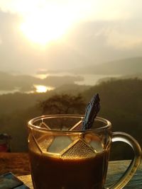 Close-up of coffee cup on table against sky during sunset