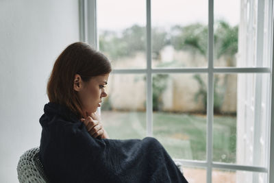 Portrait of woman looking through window