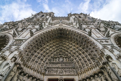 Low angle view of cathedral building in amiens against cloudy sky