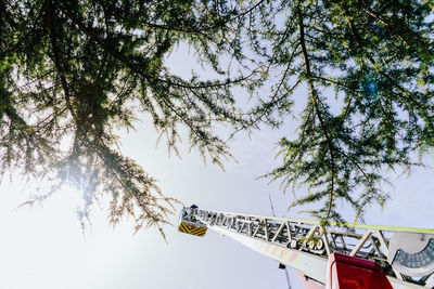 Low angle view of crane and trees against sky