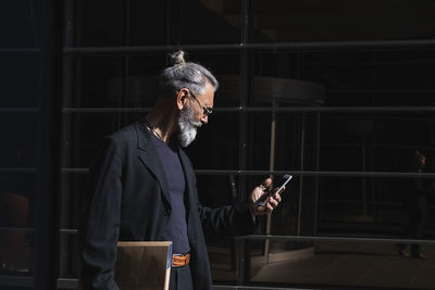 Man holding mobile phone while standing at home