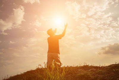 Man standing on field against sky during sunset