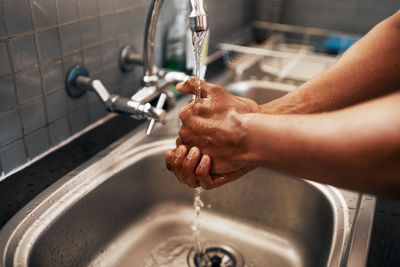 Cropped hand washing hands in sink