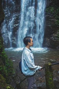 Full length of young man against waterfall