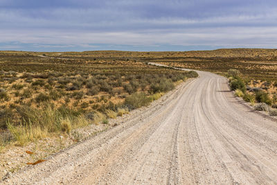 Road amidst field against sky