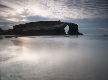 Rock formation in sea against sky