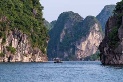 Scenic view of sea by mountains against sky