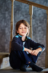 Portrait of boy sitting on railing