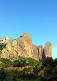 Low angle view of rocks against clear blue sky