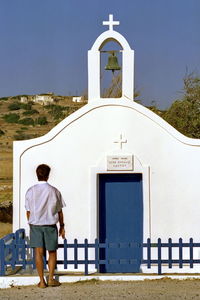 Rear view of man walking towards temple against building