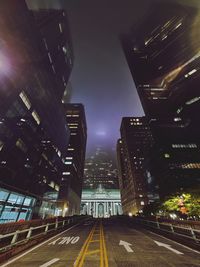 Road amidst buildings in city at night