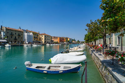Boats in canal against clear blue sky