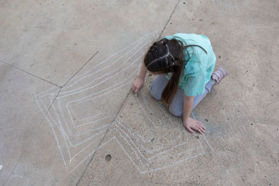 Girl draws with colorful crayons on pavement. children's drawings with chalk on wall. creative kid.