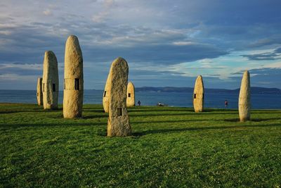 Hay bales on field by sea against sky