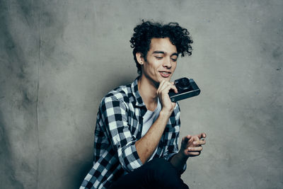 Mid adult man holding camera against wall