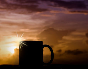 Silhouette coffee cup against sky during sunset