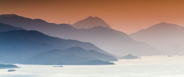 Scenic view of sea and mountains against sky during sunset