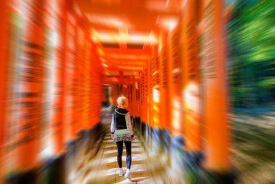 Rear view of man walking on street amidst buildings