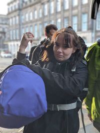 Portrait of young woman standing on street in city during winter