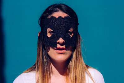 Portrait of young woman against blue background