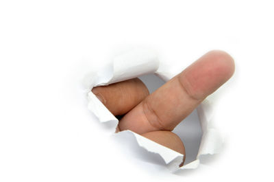 Close-up of hand holding paper over white background