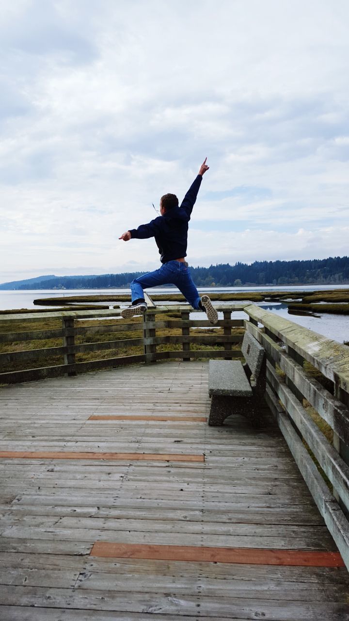 sky, full length, cloud - sky, lifestyles, leisure activity, water, mid-air, pier, cloud, rear view, jumping, sea, tranquil scene, cloudy, tranquility, lake, men, casual clothing