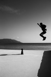 Side view of man diving in sea against sky