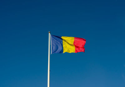 Low angle view of flag against blue sky