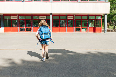 A teenage girl with a school backpack on her back runs to school. children begin to learn