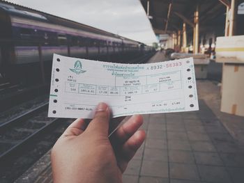 Cropped image of person holding ticket at railroad station