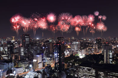Firework display in city against sky at night