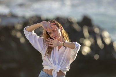 Portrait of young woman with arms raised