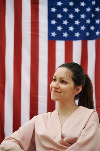 A young girl sitting with the american flag in the background. concept of america